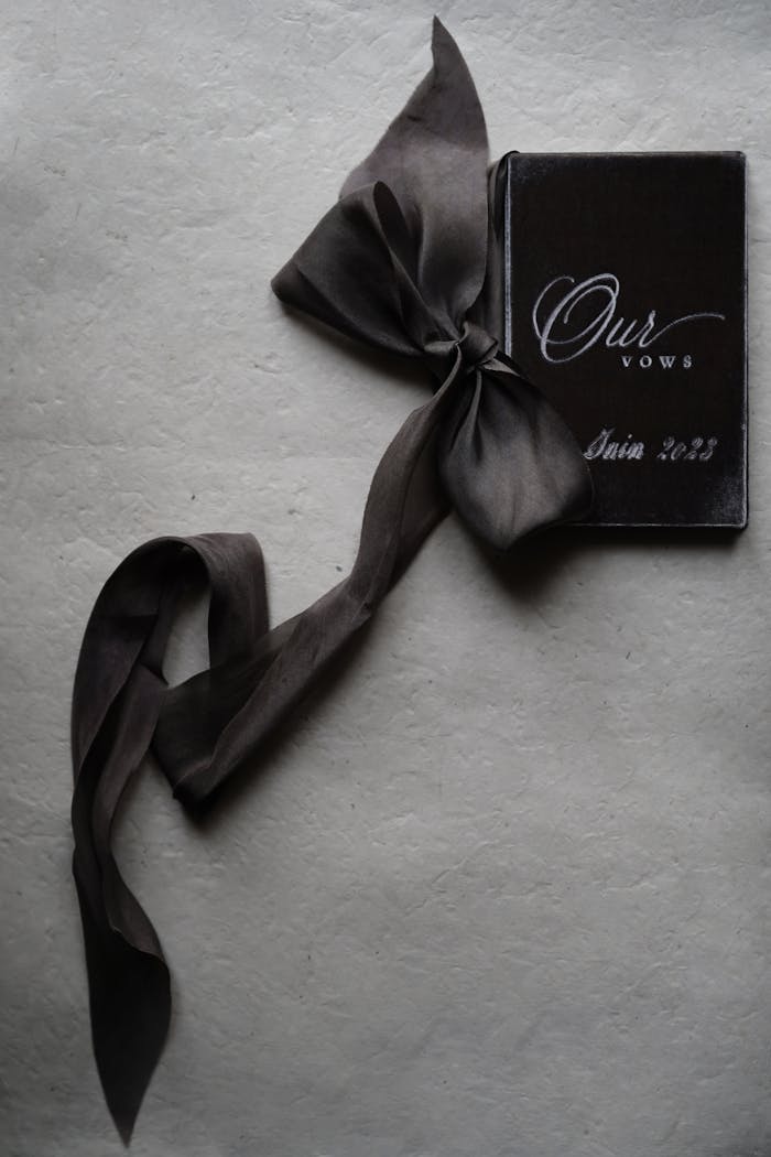 A black and white wedding vows booklet elegantly tied with a satin ribbon, 2023 edition.